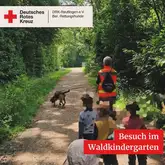 Mantrailteam mit einer Gruppe Kindern auf einem Waldweg