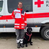 Rettungshundeteam nach der Prüfung mit der Urkunde vor einem Einsatzwagen