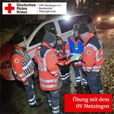 Einsatzkräfte stehen bei Nacht zusammen und Besprechen die Lage an einer Karte