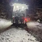 Einsatzfahrzeug der Rettungshund mit geöffnetem Kofferraum im Wald im Schnee mit eingeschaltenen Scheinwerfern