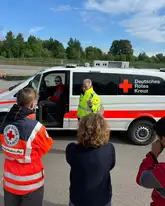 Gruppe Einsatzkräfte des DRK stehe vor einem Einsatzwagen mit einem Training für Fahrsicherheit