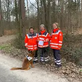Einsatzkräfte des DRK mit Einsatz Suchhund zeigen Urkunde nach erfolgreicher Prüfung in der Fläche