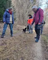 Personen gehen im Wald mit Welpe spazieren