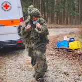 Person mit Tarnanzug vor einem Einsatzfahrzeug der Rettungshunde