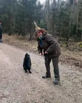 Frau mit Faschings Zauber hur im Wald mit Rettungshund vor der Suche