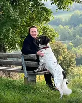 Therapiehund mit Hundeführer auf Parkbank in der Natur