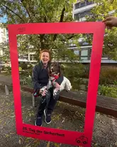 Therapiehundeteam mit Fotorahmen auf Parkbank