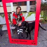 Rettungshundeführerin mit ihren Einsatzhunden macht ein Bild mit einem Rahmen auf einer Parkbankl