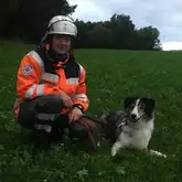 Rettungshundeteam Maya und Manu beim Einsatz sitzend in der Wiese