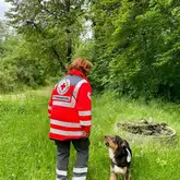 Rettungshund mit Kenndecke bellt Hundeführer in Einsatzkleidung des DRK Reutlingen an