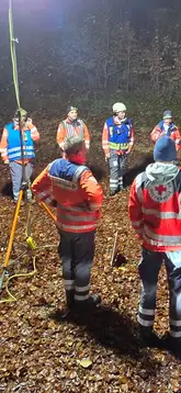 Einsatzkräfte stehen bei Nacht mit Flächenbeleuchtung im Wald