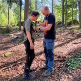 Person legt einer anderen Person einen Abseilgurt sicherheitsgurt im Wald an