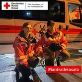 Einsatzkräfte der Rettungshunde Mantrailer mit Mantrailer Hund knien vor einem Einsatzfahrzeug nach einem Einsatz