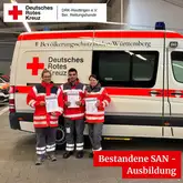 3 Einsatzkräfte der Rettungshunde Reutlingen vor einem Einsatzfahrzeug mit Urkunde