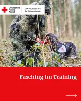Person mit Tarnanzug im Wald füttert Rettungshund mit Kenndecke