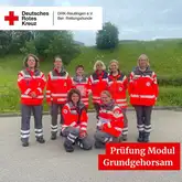 Einsatzkräfte des DRK der Rettungshunde zum Gruppenbild auf einem geteerten Platz vor einer Wiese