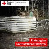 Aufgestapelte Natursteine mit Person darauf sitzend und Hund mit Kenndecke lehnt sich dagegen