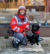 Einsatzkraft der Rettungshunde mit ihrem Einsatzhund sitzt auf einer Decke in einer Einkaufspassage