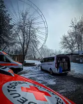 Riesenrad im Hintergrund, im vordergrund einsatzfahrzeug DRK Rettungshunde und ein privates Fahrzeug mit geöffnetem Kofferraum