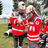 Zwei Einsatzkräfte in DRK Schutzausrüstung tauschen Informationen aus