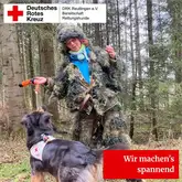 Person mit Tarnanzug tanzt vor Rettungshund